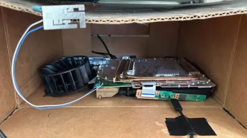 PS5 Pro internal components running in a cardboard box with an external fan